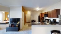 This single-story, 2-bedroom, 2-bathroom residence at Mira features an open-concept design that connects the kitchen and living areas into one cohesive space. The kitchen is equipped with rich, warm-toned cabinetry, dark granite-style countertops, a stainless steel sink, and black appliances including a refrigerator, microwave, and range. A breakfast bar extends from the kitchen counter, creating a natural division between the cooking and living spaces while maintaining an open feel.

The living area features plush carpeting and is accented by a bold warm-toned accent wall, adding visual depth to the space. Track lighting in the kitchen area provides focused illumination, while the overall layout benefits from a bright, open corridor leading toward the entry. The entryway is defined by neutral tones and includes closet access, offering practical storage upon arrival.

The single-floor layout ensures easy navigation throughout the residence. With two full bathrooms complementing the two bedrooms, this home is well-suited for shared living or those seeking dedicated guest accommodations. The overall design balances functionality with a welcoming, comfortable ambiance.