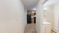 Located at 106 W River Dr in Manchester, NH, this one-bedroom, one-bathroom unit offers a practical and well-organized single-floor layout. The space includes two living areas, providing flexibility for both a dedicated living room and a separate dining or sitting area. One living space features a window unit for climate control, baseboard heating, and a natural light-filled window with outdoor views, while the second living area is accented by a classic chandelier overhead — both finished with neutral carpet flooring and warm beige walls throughout.

The kitchen is efficiently designed with warm wood cabinetry, dark granite-style countertops, tile flooring, and a full suite of black appliances including an electric range, built-in microwave, dishwasher, and a stainless steel sink — making it a fully functional cooking space.

The bedroom offers a comfortable, carpeted retreat with a spacious closet featuring sliding panel doors and baseboard heating. The bathroom includes a full tub and shower combo with clean white tile surround and tile flooring, maintaining a simple and functional aesthetic.

Throughout the unit, the consistent use of neutral tones, carpet, and baseboard heating creates a cohesive and low-maintenance living environment.