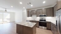 This single-floor residence showcases a thoughtfully designed open-concept layout, with light wood-style flooring flowing through the main living areas and recessed lighting creating a bright, welcoming atmosphere. The kitchen serves as the focal point of the space, featuring dark mocha-toned cabinetry, a white subway tile backsplash, and a full suite of stainless steel appliances, including an electric range, built-in microwave, dishwasher, and French door refrigerator. A substantial center island with a granite countertop provides both additional workspace and a natural gathering point. The open layout seamlessly connects the kitchen to the living area, which offers access to a balcony through a sliding glass door and is outfitted with a ceiling fan. The bedroom is generously sized, carpeted for comfort, and features two large windows that invite natural light and exterior views, along with a ceiling fan. The bathroom is well-appointed with a granite-topped vanity with dark cabinetry, a tiled combination shower and tub, and light wood-style flooring. A spacious walk-in closet with built-in shelving and hanging rods is directly accessible from the bathroom, offering excellent storage throughout.
