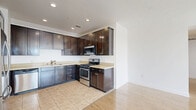 This contemporary apartment in Los Angeles offers 1,170 square feet of thoughtfully designed living space. The open floor plan showcases a seamless flow between the living areas, highlighted by gleaming light-colored hardwood floors throughout. The kitchen is a standout feature, boasting dark wood cabinetry, stainless steel appliances, and a subway tile backsplash, creating a striking contrast against the light-toned countertops.

The apartment comprises three bedrooms, including a spacious primary suite measuring 210 square feet. Two well-appointed bathrooms feature modern fixtures, with at least one showcasing a glass-enclosed shower and neutral-toned tile flooring. Ample natural light floods the space through large windows, some of which open onto a balcony offering scenic city views.

Additional amenities include recessed lighting, a hallway for easy navigation between rooms, and two closets for storage. The unit's clean lines, neutral color palette, and contemporary finishes create a fresh and inviting atmosphere, perfect for modern urban living in the heart of Los Angeles.