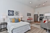 Located at 1099 Boulevard SE in Atlanta's Grant Park neighborhood, this single-floor studio offers a thoughtfully designed open-concept layout that maximizes functionality and livability. Light wood-tone flooring flows consistently throughout the entire unit, creating a cohesive and airy feel.

The living and sleeping area occupies a generous open space bathed in natural light from a bank of large windows fitted with roller shades. Soaring ceilings amplify the sense of openness, while a decorative room divider provides a flexible way to define separate zones within the space.

The kitchen is sleek and fully equipped, featuring white cabinetry extending to the ceiling, granite countertops, a subway tile backsplash, and a complete suite of stainless steel appliances including a refrigerator, range, microwave, and dishwasher. It opens directly to the living area, making the space ideal for everyday convenience.

The bathroom is clean and modern, with a white vanity cabinet, granite countertop, a large mirror with overhead lighting, wood-look flooring, and a shower-tub combination. The overall design palette throughout the unit is neutral and bright, with white walls and minimalist finishes that create a calm, contemporary ambiance well-suited to urban living in Atlanta.