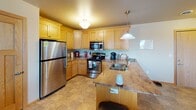 Located at 2875 36th Ave S in Grand Forks, North Dakota, this single-floor home offers a well-designed, functional layout with comfortable living spaces throughout. The open-concept kitchen flows seamlessly into the main living area, creating an inviting, connected atmosphere. The kitchen is appointed with warm oak cabinetry, granite-style countertops, stainless steel appliances including a refrigerator, range, and over-the-range microwave, and a peninsula with a double sink and pendant lighting overhead. The adjacent living room features carpet flooring, a tile-surround fireplace with a wall-mounted television above, and a door providing direct access to an outdoor area. A secondary sitting room offers additional flexible living space with carpet, a window, and an exterior door, allowing for natural light and easy outdoor access. The bedrooms are carpeted and comfortably sized, with windows that bring in natural light. Two full bathrooms are present, each featuring oak vanity cabinetry, granite-style countertops, large mirrors with overhead lighting, and tile flooring. The home's consistent use of warm wood tones, neutral wall colors, and tile flooring in transitional areas lends a cohesive and practical character throughout.