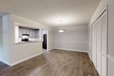 This single-floor residence offers a well-organized layout with a series of thoughtfully updated spaces. The living room is anchored by dark hardwood-style flooring, neutral gray walls, and a textured ceiling, with natural light streaming in through a glass door that opens to a private balcony overlooking greenery outside. Adjacent to the living area, the dining space features the same rich flooring, a pendant light fixture overhead, and a pass-through opening that connects directly to the kitchen. A chair rail detail along the dining room walls adds a subtle architectural touch.

The kitchen is well-appointed with gray shaker-style cabinetry, granite-look countertops, a white subway tile backsplash, and black appliances including an electric range, dishwasher, and refrigerator. Wood-look tile flooring runs throughout the kitchen for easy maintenance.

The two bedrooms are finished with plush carpeting and receive natural light through multiple windows fitted with blinds. One bedroom includes a double sliding-door closet, while another features two windows for added brightness.

The bathrooms offer granite vanity countertops, gray cabinetry, framed mirrors, and a tiled shower-tub combination, maintaining a consistent, updated aesthetic throughout the home.