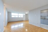 Located at 3875 Sheppard Ave E in Toronto's Scarborough district, this one-bedroom, one-bathroom unit offers a practical and well-laid-out living space across a single floor. Warm parquet flooring flows throughout the living areas and bedroom, adding a classic character to the interior. The spacious living room is highlighted by a wide bank of windows that fill the space with natural light and frame open views of the surrounding Toronto cityscape and greenery below.

The kitchen is efficiently designed with modern grey cabinetry, granite-style countertops, a double stainless steel sink, a white electric range, and marble-look tile flooring — offering both functionality and a clean aesthetic. The bedroom is a comfortable size, featuring its own large window with panoramic views, a built-in closet for storage, and the same warm parquet flooring found throughout.

The bathroom is finished with clean white tile surrounding a full-size soaker tub with an overhead shower. Baseboard heating units are present throughout the unit, ensuring year-round comfort. The overall ambiance is bright, clean, and straightforward, making this unit a well-organized home in a convenient Toronto location.