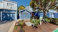 Located at 801 Dutton in Santa Rosa, California, this two-story residential community presents a cohesive architectural identity through its distinctive blue and white exterior buildings accented with warm orange door details. The community is spread across a well-organized grounds that include clearly marked parking areas, reserved spaces, and wide internal driveways for easy navigation.

A dedicated leasing office, housed in a charming blue outbuilding with white trim, serves as the welcoming hub of the community and is accompanied by a landscaped entry with flowering plants and shrubbery. Residents benefit from a communal outdoor gathering area shaded by tall, mature trees, furnished with benches and a picnic table beneath a blue umbrella — an inviting space for relaxation or socializing.

The grounds are generously lined with established trees, including towering redwoods, providing natural shade and a sense of seclusion throughout the property. Lush greenery, trimmed hedges, and flowering plants are thoughtfully integrated across the community, enhancing its curb appeal. A fenced perimeter along portions of the property adds privacy for residents. Overall, the community offers a well-maintained, tree-canopied setting with practical amenities and a friendly neighborhood atmosphere in the heart of Santa Rosa.