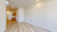 Located at 2701 Shattuck Ave in Berkeley, California, this single-floor unit offers a clean, modern design with a practical and efficient layout. Throughout the space, light-toned wood-style flooring creates a bright, cohesive aesthetic that complements the crisp white walls and recessed lighting overhead.

The main living area is open and versatile, with smooth white walls, multiple electrical outlets, and ample room for flexible furnishing arrangements. Large windows and a glass-paneled entry door face the street, flooding the space with natural light and providing views of the surrounding Berkeley neighborhood.

The kitchenette is a standout feature, outfitted with warm honey-toned wood cabinetry spanning both upper and lower sections. It includes a smooth-top electric cooktop, built-in microwave, stainless steel sink with modern faucet, light-colored countertops, and a full-size refrigerator — providing comprehensive cooking and storage functionality within a compact footprint.

The bathroom is designed with accessibility in mind, featuring stainless steel grab bars positioned around the toilet and along the walls, a wall-mounted sink, and the same wood-style flooring that runs throughout the unit. The layout provides generous maneuvering space, reflecting a thoughtful, inclusive design approach.

Overall, the space presents a well-maintained, move-in ready environment with modern finishes suited for a range of uses.
