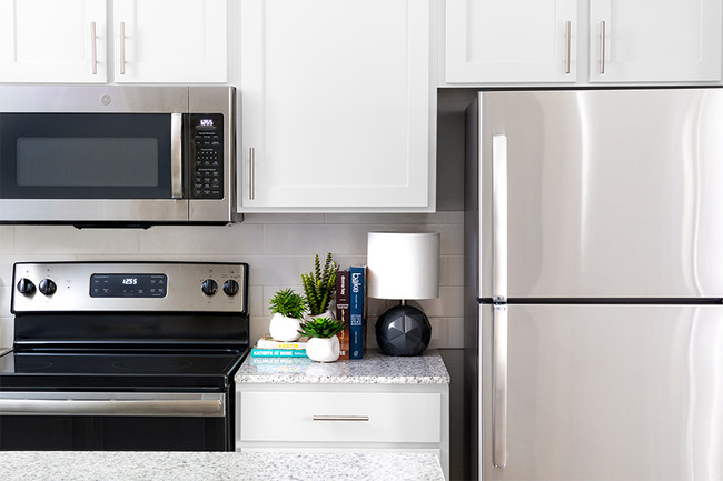 Kitchens with premium granite countertops and stainless steel appliances - Reserve At Beachline Apartments