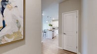 This thoughtfully designed single-floor residence offers two bedrooms and two bathrooms within a comfortable and efficiently laid-out floor plan. The open-concept kitchen and living area serves as the heart of the home, featuring a central island with granite countertops and seating for two, white shaker-style cabinetry, stainless steel appliances, and pendant lighting overhead. Light wood-style flooring flows throughout the main living areas, complementing the bright, neutral palette. The living room is anchored by a soft blue accent wall and large windows with an exterior door that invite generous natural light and outdoor views. Both bedrooms are carpeted and well-sized, each offering large windows with outdoor views and ample closet storage. The primary bedroom includes a spacious walk-in closet equipped with wire shelving systems. The primary bathroom features a long granite-topped double vanity with white cabinetry, a large mirror, and a soaking tub. The second bathroom is equally well-finished, with matching granite countertops, light wood flooring, and clean white millwork throughout. Two dedicated closets provide additional storage. The overall ambiance is modern and cohesive, with consistent finishes that lend a polished, move-in-ready feel to the entire space.