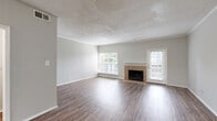 This two-floor residence offers a well-organized and functional layout with clean, neutral finishes throughout. The main living area is a standout feature, showcasing rich hardwood-style flooring, a tile-surround fireplace with a classic white mantel, and multiple windows that allow generous natural light to fill the space. A glass-paned exterior door leads to the outdoors, enhancing the bright and open feel of the room. Textured ceilings and crown molding add architectural character throughout.

The kitchen is well-appointed with white cabinetry, white countertops, and a full suite of black appliances including a range, microwave, refrigerator, and dishwasher. A window above the sink brings in additional natural light, making the space both practical and pleasant.

The bathrooms are finished with white vanity cabinetry, light stone-look countertops, and wood-style flooring. One bathroom includes a soaking tub alongside a separate shower stall, providing a spa-like functionality. Additional areas of the home feature plush carpeting, offering a comfortable contrast to the hard flooring found elsewhere.

A staircase connects the two floors, and the dollhouse view reveals a well-proportioned layout with distinct zones for living, dining, and private spaces, making this a versatile and comfortable home.