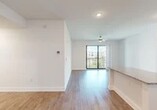 This well-appointed one-bedroom, one-bathroom unit offers a thoughtfully designed single-floor layout with a clean, modern aesthetic. Wood-style flooring runs consistently throughout the space, complementing crisp white walls and creating a cohesive, contemporary feel.

The open-concept kitchen is outfitted with white shaker cabinetry, granite countertops, stainless steel appliances including a refrigerator, range, and microwave, and a peninsula that provides additional counter space and separates the kitchen from the living area. Recessed lighting illuminates the kitchen efficiently.

The living room benefits from a ceiling fan and a glass sliding door that opens to a private balcony, offering natural light and outdoor views. The bedroom features a tray ceiling with a ceiling fan, a window with natural light, and direct access to a generously sized walk-in closet equipped with wire shelving systems for organized storage.

The bathroom is well-finished with a granite-topped white vanity, a large mirror, and a glass-enclosed walk-in shower. A dedicated laundry area houses a stacked full-size washer and dryer unit, adding notable convenience. A hallway connects the rooms efficiently, completing this well-organized residential layout.