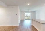 This well-appointed one-bedroom, one-bathroom unit offers a thoughtfully designed single-floor layout with a clean, modern aesthetic. Wood-style flooring runs consistently throughout the space, complementing crisp white walls and creating a cohesive, contemporary feel.

The open-concept kitchen is outfitted with white shaker cabinetry, granite countertops, stainless steel appliances including a refrigerator, range, and microwave, and a peninsula that provides additional counter space and separates the kitchen from the living area. Recessed lighting illuminates the kitchen efficiently.

The living room benefits from a ceiling fan and a glass sliding door that opens to a private balcony, offering natural light and outdoor views. The bedroom features a tray ceiling with a ceiling fan, a window with natural light, and direct access to a generously sized walk-in closet equipped with wire shelving systems for organized storage.

The bathroom is well-finished with a granite-topped white vanity, a large mirror, and a glass-enclosed walk-in shower. A dedicated laundry area houses a stacked full-size washer and dryer unit, adding notable convenience. A hallway connects the rooms efficiently, completing this well-organized residential layout.