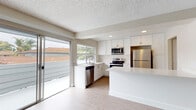 Located at 612 Los Arbolitos Blvd in Oceanside, California, this single-floor residence offers a clean, contemporary interior with consistent light-toned luxury vinyl plank flooring and textured ceilings throughout. The open-concept kitchen is a standout feature, outfitted with crisp white shaker cabinetry, quartz countertops, and a full suite of stainless steel appliances including a refrigerator, electric range, microwave, and dishwasher. A sliding glass door connects the kitchen and living area directly to an outdoor space, inviting natural light and fresh air into the home. The living room is generously proportioned, featuring a ceiling fan and additional sliding glass door access that further enhances the bright, airy atmosphere. Multiple bedrooms offer a calm, neutral palette with warm-toned vinyl flooring and natural light provided by outdoor-facing windows. The bathrooms are thoughtfully updated, featuring white shaker vanities with quartz countertops, modern fixtures, and a tub-shower combination. Throughout the residence, clean white trim, soft neutral wall tones, and consistent flooring create a cohesive and move-in-ready environment well-suited to the sunny Southern California lifestyle.