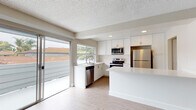 Located at 612 Los Arbolitos Blvd in Oceanside, California, this single-floor residence offers a clean, contemporary interior with consistent light-toned luxury vinyl plank flooring and textured ceilings throughout. The open-concept kitchen is a standout feature, outfitted with crisp white shaker cabinetry, quartz countertops, and a full suite of stainless steel appliances including a refrigerator, electric range, microwave, and dishwasher. A sliding glass door connects the kitchen and living area directly to an outdoor space, inviting natural light and fresh air into the home. The living room is generously proportioned, featuring a ceiling fan and additional sliding glass door access that further enhances the bright, airy atmosphere. Multiple bedrooms offer a calm, neutral palette with warm-toned vinyl flooring and natural light provided by outdoor-facing windows. The bathrooms are thoughtfully updated, featuring white shaker vanities with quartz countertops, modern fixtures, and a tub-shower combination. Throughout the residence, clean white trim, soft neutral wall tones, and consistent flooring create a cohesive and move-in-ready environment well-suited to the sunny Southern California lifestyle.