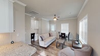 Located at 1367 Benbrook Blvd in Huntsville, Alabama, this single-floor home offers a thoughtfully designed layout with modern finishes throughout. The open-concept living and dining area is finished with warm wood-look flooring, crown molding, and a ceiling fan, creating an inviting and cohesive atmosphere. Large windows fitted with white blinds allow natural light to flow generously through the space. The living area comfortably accommodates a seating arrangement centered around a media console, while the adjacent dining area provides a dedicated space for meals.

The kitchen is a standout feature, showcasing crisp white shaker-style cabinetry that extends to the ceiling, granite countertops, a classic subway tile backsplash, and stainless steel appliances including a range, microwave, and dishwasher. A built-in desk nook off the main living area adds a practical workspace element to the floor plan.

The bedroom is a calm retreat, featuring crown molding, a ceiling fan, hardwood-style flooring, and a large window that brings in ample natural light. The bathroom is finished with granite countertops, a framed glass walk-in shower with dark bronze hardware, and tile flooring, completing this clean and cohesive home.