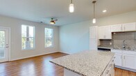 This single-floor residence offers a cohesive, modern design highlighted by warm hardwood flooring that extends seamlessly throughout every room. The open-concept kitchen is a standout feature, equipped with crisp white shaker cabinetry, granite countertops, a tile backsplash, stainless steel appliances, and a central island with pendant lighting overhead — ideal for both cooking and casual dining. The kitchen flows naturally into a spacious living and dining area, where multiple windows allow abundant natural light and views of the surrounding greenery, complemented by a ceiling fan for year-round comfort.

A dedicated entry area provides a welcoming transition into the home, with a glass-paneled door and additional windows that further brighten the interior. The hallway connecting the private rooms is clean and well-lit, featuring recessed lighting and classic panel-style white doors. The bedrooms are generously proportioned, each offering multiple windows with outdoor views and ceiling fans, creating bright and airy retreats. The bathroom continues the home's refined aesthetic with granite countertops, white cabinetry, an undermount sink, and a large mirror. Throughout, neutral wall tones and consistent finishes create a polished, move-in ready atmosphere.