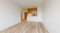 Located at 1101 National Ave in San Bruno, California, this one-bedroom, one-bathroom residence offers a practical and efficient single-floor layout. Light wood laminate flooring runs consistently throughout the entire unit, creating a clean, cohesive aesthetic from room to room.

The open-concept living and kitchen area forms the heart of the home. The living space is bright and airy, featuring white walls and a large window that allows natural light to fill the room. The kitchen is defined by warm honey-toned wood cabinetry, granite-style countertops, a built-in breakfast bar, and black appliances including a range and refrigerator. A skylight-style ceiling fixture provides additional overhead lighting.

The bedroom is a well-proportioned, private retreat with crisp white walls, light wood flooring, and a window fitted with blinds that offer a view of surrounding greenery. A wall-mounted heating unit adds functional convenience.

The bathroom features a clean, neutral design with a full tub and shower combination enclosed by a curved chrome curtain rod. A warm wood vanity with an integrated sink and mirror completes the space. The light flooring and white finishes give the bathroom a bright, airy feel. Overall, the residence presents a functional and well-maintained living space in a convenient San Bruno location.