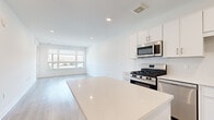 Located at 72 Eagle Rock Ave in East Hanover, NJ, this modern 1-bedroom, 1-bathroom residence offers a thoughtfully designed open-concept layout with clean lines and a bright, contemporary aesthetic throughout. Light-toned hardwood flooring flows seamlessly across the entire unit, enhancing the airy feel of each room.

The kitchen is a standout feature, showcasing crisp white cabinetry, a suite of stainless steel appliances including a gas range, over-the-range microwave, and French door refrigerator, complemented by a large center island with a white quartz countertop — ideal for both meal preparation and casual dining. The kitchen opens directly into the living area, which benefits from a large picture window and a sliding glass door that floods the space with natural light and provides outdoor access.

The bedroom is a comfortable, well-proportioned retreat with light-filled walls, recessed lighting, and ample space for furnishings. The bathroom features a full soaking tub and shower combo, finished with elegant white subway-style tile from floor to ceiling, paired with modern brushed nickel hardware. Recessed lighting throughout the unit adds a polished, modern touch to this well-appointed East Hanover residence.