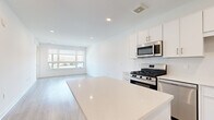 Located at 72 Eagle Rock Ave in East Hanover, NJ, this modern 1-bedroom, 1-bathroom residence offers a thoughtfully designed open-concept layout with clean lines and a bright, contemporary aesthetic throughout. Light-toned hardwood flooring flows seamlessly across the entire unit, enhancing the airy feel of each room.

The kitchen is a standout feature, showcasing crisp white cabinetry, a suite of stainless steel appliances including a gas range, over-the-range microwave, and French door refrigerator, complemented by a large center island with a white quartz countertop — ideal for both meal preparation and casual dining. The kitchen opens directly into the living area, which benefits from a large picture window and a sliding glass door that floods the space with natural light and provides outdoor access.

The bedroom is a comfortable, well-proportioned retreat with light-filled walls, recessed lighting, and ample space for furnishings. The bathroom features a full soaking tub and shower combo, finished with elegant white subway-style tile from floor to ceiling, paired with modern brushed nickel hardware. Recessed lighting throughout the unit adds a polished, modern touch to this well-appointed East Hanover residence.