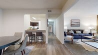 This single-floor, 2-bedroom, 2-bathroom residence offers a thoughtfully designed open-concept layout that connects the kitchen, dining, and living areas seamlessly. Wood-style flooring flows throughout the main living spaces, creating a cohesive and contemporary feel.

The kitchen is equipped with rich dark-espresso cabinetry, granite-style countertops, stainless steel appliances including a range, microwave, and dishwasher, and a breakfast bar that provides casual seating and opens to the dining area. The dining space comfortably accommodates a round table and chairs, with clean white walls enhancing its bright, airy character.

The living room features plush carpeting, a sliding glass door that invites natural light and provides outdoor access, and ample space for comfortable furnishings. A hallway connects the living spaces to the bedrooms and bathrooms, maintaining a clear and functional flow throughout.

The generously sized primary bedroom includes plush carpet, a ceiling fan, and floor-to-ceiling mirrored sliding closet doors. The bathrooms feature dark cabinetry with granite-style countertops and wood-style tile flooring. The second bedroom offers a cozy, versatile space suitable for guests or a home office. Overall, the residence presents a clean, modern aesthetic with practical, well-considered finishes throughout.