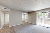 Located in Paso Robles, CA, this single-floor, three-bedroom residence offers a well-organized layout with a living room, dedicated kitchen, combined kitchen and dining area, hallway, and five closets providing ample storage throughout. The living room is generously sized, featuring plush carpeting, a textured ceiling, neutral warm-gray walls, and a sliding glass door with vertical blinds that fills the space with natural light and offers views of the surrounding greenery. The kitchen is thoughtfully appointed with gray shaker-style cabinetry, light stone-effect countertops, white appliances including a refrigerator, dishwasher, electric range, and a stainless steel sink, all set over light wood-look flooring with recessed lighting above. The adjacent dining area extends the kitchen's functionality and benefits from a window view of the outdoors. Each of the three bedrooms is carpeted and features neutral tones, textured ceilings, and closet storage. The primary bedroom includes two closet doors, while the additional bedrooms each offer individual closets. Windows in the secondary bedrooms allow natural light to brighten each room. Clean white trim and baseboards throughout unify the home's understated, move-in-ready aesthetic.