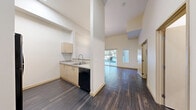 Located at 522 N 85th St in Seattle's Greenwood neighborhood, this efficiently designed studio offers a thoughtful single-floor layout that maximizes every square foot. Soaring ceilings create a sense of openness well beyond the unit's physical footprint, while dark hardwood-style flooring runs throughout, providing a sleek, modern aesthetic.

The open-concept kitchen and living area form the heart of the space. The kitchen is outfitted with light maple cabinetry, granite-look countertops, a stainless steel range, a black dishwasher, and an undermount sink — offering ample storage and a clean, contemporary finish. The kitchen flows seamlessly into the living area, which is bathed in natural light from large sliding glass doors that open to a private outdoor patio, framing views of surrounding greenery.

The bathroom features a full soaking tub and shower combination with chrome fixtures, a granite-topped vanity, and matching hardwood-style flooring for a cohesive look. A dedicated laundry area houses a stacked washer and dryer unit alongside wire shelving for additional storage. Crisp white walls and high ceilings throughout lend the space an airy, open ambiance, making this studio a well-appointed and functional urban retreat.