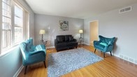 Located at 6242 Roosevelt Blvd in Philadelphia's 19149 neighborhood, this single-floor residence offers a well-organized layout with distinct living, sleeping, dining, and kitchen areas. The living room is a welcoming space highlighted by warm hardwood flooring, neutral gray walls, and a large window that draws in natural light. The room offers generous proportions, providing ample space for comfortable seating arrangements. Adjacent to the living area, the combined dining and kitchen space features light tile flooring, a chandelier overhead, and a window at the far end that brightens the kitchen. The kitchen is equipped with standard appliances, including a refrigerator and stove. The bedrooms are carpeted for comfort and feature gray walls, large windows with outdoor views of the surrounding neighborhood, and ceiling fixtures. Each bedroom provides a calm, functional retreat with adequate space for furnishings. The bathroom is clean and efficiently designed, featuring a full-size soaking tub, white subway tile surround, light gray floor tiles, and a white vanity. Throughout the space, a consistent neutral color palette and clean finishes contribute to a cohesive, move-in-ready atmosphere.