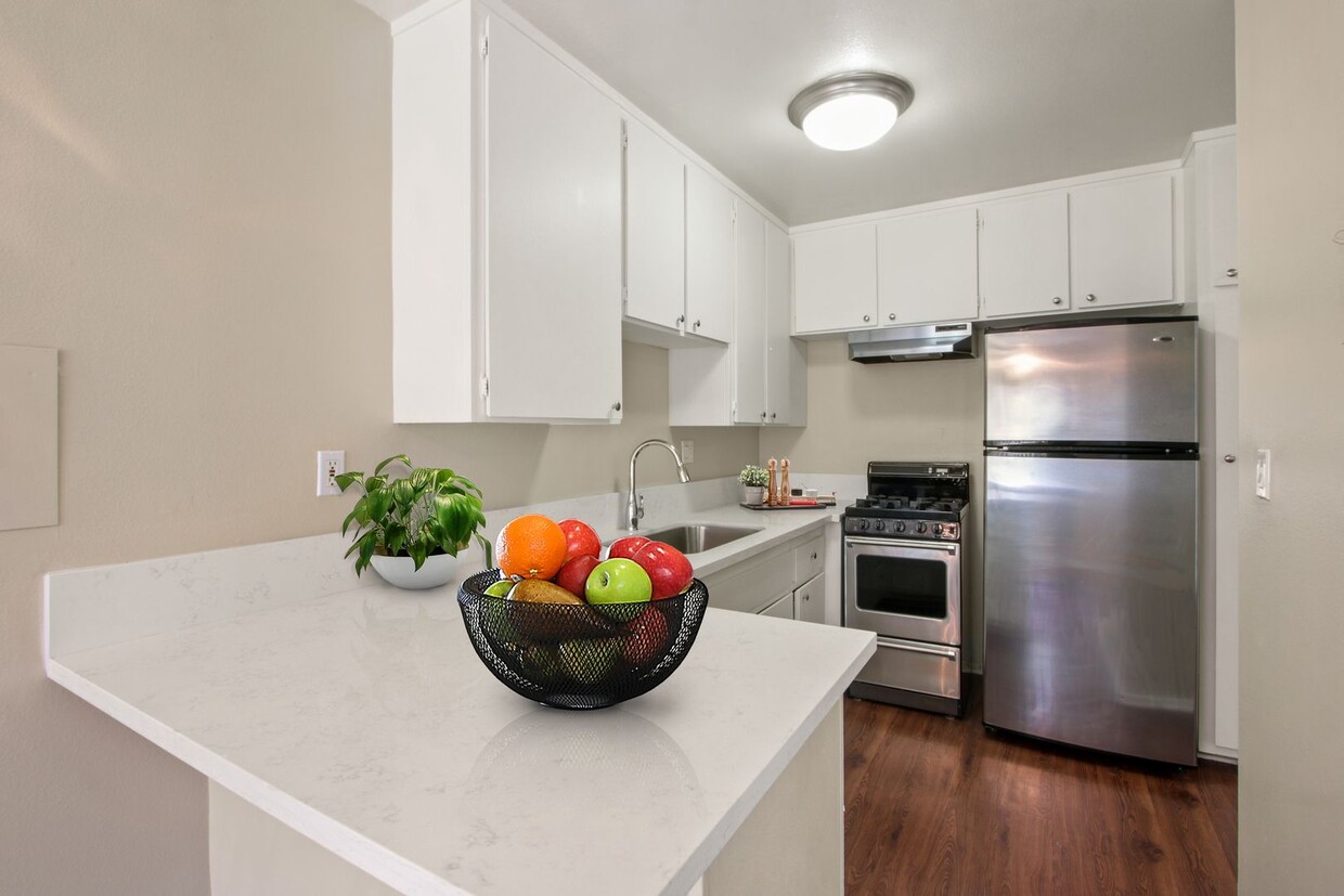 Cocina con electrodomésticos de acero inoxidable, un refrigerador de dos puertas, estufa a gas de más de una campana extractora, gabinetes de color blanco - Seville Townhouse