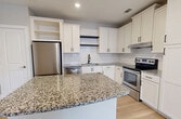 This 670 square foot apartment in Suwanee, GA offers a thoughtful blend of style and functionality. The modern kitchen is a standout feature, boasting crisp white cabinetry, granite countertops, and stainless steel appliances. A generous island provides additional prep space and casual seating.

The single bedroom, measuring 160 square feet, is carpeted for comfort and features a ceiling fan and large windows that flood the space with natural light. The bathroom is elegantly appointed with a tub/shower combination and sleek fixtures.

The open concept living area showcases beautiful hardwood flooring and ample windows, creating a bright and airy atmosphere. A dedicated laundry area with full-size washer and dryer adds convenience to daily living.

Throughout the apartment, neutral tones and modern finishes create a cohesive, contemporary aesthetic. Ceiling fans, recessed lighting, and window treatments are thoughtful additions that enhance comfort and style. With its efficient layout and high-quality features, this apartment offers a perfect blend of comfort and modern living in a compact space.