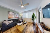 Located at 2000 Stirling Rd in Hollywood, FL, this well-appointed one-bedroom, one-bathroom residence offers a thoughtfully designed single-floor layout. The open-concept kitchen, dining, and living area forms the heart of the home, showcasing crisp white shaker cabinetry, granite countertops, a white subway tile backsplash, stainless steel appliances, and a center island with seating — all illuminated by track lighting overhead and set atop rich hardwood-style flooring. The living room offers a relaxed ambiance with a ceiling fan, large windows that invite natural light, and direct access to the patio, providing a seamless indoor-outdoor connection. The bedroom features a warm accent wall, a ceiling fan, natural light from a large window, and direct access to the bathroom. The bathroom is finished with granite vanity countertops, white cabinetry, large-format neutral tile, and a full soaking tub with shower. Additional conveniences include two closets, a dedicated laundry area, a utility room, and an entrance foyer. The overall aesthetic is clean and contemporary, with a neutral palette and modern fixtures throughout.