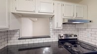 Located at 917 7th Avenue in Garner, North Carolina, this single-floor home offers a well-organized layout with functional living spaces throughout. The open living area features neutral-toned carpet and flows directly into the kitchen, creating a connected and practical floor plan. The kitchen is a standout feature, outfitted with white cabinetry, dark granite countertops, a classic white subway tile backsplash with dark grout, wood-look tile flooring, and a stainless steel electric range with a ventilation hood — combining style with everyday utility. Multiple bedrooms are carpeted and finished with neutral walls, offering a clean and comfortable environment. Each room features windows with horizontal blinds that allow natural light to filter in, and closet access is provided for convenient storage. The bathrooms are appointed with dark granite vanity countertops, undermount sinks, brushed nickel fixtures, wall-mounted lighting above large mirrors, and a tub/shower unit with smooth surround walls. The textured wall finish throughout the home adds subtle character. Overall, the space presents a clean, move-in-ready interior with consistent finishes that balance practicality and modern aesthetics.