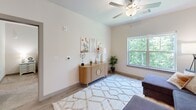 This thoughtfully designed one-bedroom, one-bathroom residence in North Chesterfield, Virginia offers a efficient and comfortable single-floor layout. The open-concept living and kitchen area serves as the heart of the space, where the kitchen impresses with dark espresso cabinetry, granite countertops, stainless steel appliances, and a peninsula with bar seating — ideal for both cooking and casual dining. The living room is bathed in natural light from large windows framing lush, wooded views outside, and is fitted with a ceiling fan for added comfort. Light wood-style flooring flows throughout the main living areas, complementing the clean, neutral palette. The generously sized bedroom features plush carpeting, large windows overlooking the greenery, and ample room for a full furniture arrangement. Adjacent to the bedroom is a dedicated walk-in closet outfitted with wire shelving systems, providing excellent organization and storage capacity. The full bathroom includes a combined tub and shower, wood-style flooring, and clean, bright finishes. The overall ambiance is modern and inviting, with a cohesive design aesthetic that balances functionality and comfort throughout.
