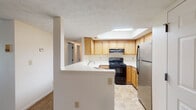 Located at 2907 N High St in Columbus, Ohio's vibrant Clintonville neighborhood, this single-floor unit offers a well-organized layout with a variety of functional living spaces. The kitchen is a standout feature, outfitted with warm-toned wood cabinetry, a stainless steel refrigerator, a black electric range, and a peninsula with a built-in sink ideal for meal prep. A skylight overhead floods the kitchen with natural light, creating a bright and welcoming atmosphere. Tile flooring runs throughout the kitchen, offering easy maintenance.

The open living area is generously sized, featuring plush wall-to-wall carpeting and a textured ceiling. Large sliding glass doors provide direct outdoor views and bathe the space in abundant natural light. The layout flows seamlessly from the living area toward the kitchen peninsula, supporting an open and connected feel.

The bedrooms are comfortably sized with soft carpeting, textured ceilings, and windows that invite natural light. One bedroom includes a standard closet, while another is complemented by a spacious walk-in closet equipped with multiple clothing rods and tile flooring — offering exceptional storage capacity.

The bathroom features a full soaking tub with white tile surround, a vanity with warm wood cabinetry, a large mirror, and tile flooring, completing this functional and comfortable home.