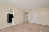This single-story unit offers a practical and comfortable layout across two bedrooms, one bathroom, a kitchen, and a dedicated closet. The open living area is finished with soft wall-to-wall carpeting and neutral walls that create a warm, welcoming atmosphere. A large window allows natural light to fill the space, enhancing the bright and airy feel. The living area flows into the secondary bedroom, also carpeted and featuring a ceiling fan and its own window overlooking the outdoors.

The kitchen is outfitted with crisp white cabinetry, granite-style countertops, and tile flooring. It includes a full suite of appliances such as a range and refrigerator, along with ample counter and storage space arranged in an efficient layout.

The spacious primary bedroom includes a ceiling fan, access to a walk-in closet with built-in shelving and hanging rods, and a direct connection to the full bathroom. The bathroom features a tub-shower combination with tile surround, a toilet, vanity with a single sink, and tile flooring.

Throughout the unit, a consistent neutral color palette and textured ceilings contribute to a cohesive and tidy aesthetic, making this a well-organized and livable space.