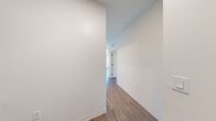 Located at 61 Braintree St in Boston's Allston neighborhood, this modern 2-bedroom, 2-bathroom unit offers a thoughtfully designed single-floor layout with a clean, contemporary aesthetic throughout. Warm hardwood-style flooring flows consistently across the living areas, hallways, and bedrooms, complementing the crisp white walls and black hardware accents that define the unit's design language.

The kitchen is well-appointed with stainless steel appliances, including a full-size refrigerator, dishwasher, range, and microwave. Two-toned cabinetry — white uppers paired with natural wood lowers — sits above a white subway tile backsplash, lending the space a modern yet welcoming character. A large window in the kitchen area fills the space with natural light.

The living area features a striking bank of floor-to-ceiling windows offering panoramic views of the surrounding Boston cityscape, flooding the room with natural light. Both bedrooms are well-proportioned, with the primary bedroom offering comfortable dimensions and city views. A dedicated closet provides useful storage.

The two bathrooms are finished with modern fixtures and matte black hardware. One bathroom features large-format tile flooring, a wood-toned vanity, and a tub-shower combination, while the second showcases a frameless glass walk-in shower with white vertical subway tile and a sleek black door frame. Three hallways connect the rooms, contributing to an intuitive and functional floor plan.