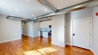 This thoughtfully designed 4-bedroom, 2-bathroom single-floor unit blends industrial character with modern finishes. Warm, honey-toned hardwood floors run throughout, complemented by soft gray walls and recessed lighting that create a bright, welcoming atmosphere. A striking architectural feature is the exposed silver ductwork that traverses the open living and kitchen area, lending a loft-inspired aesthetic to the space.

The open-concept kitchen is equipped with stainless steel appliances—including a range, microwave, dishwasher, and refrigerator—alongside white shaker cabinetry and a classic subway tile backsplash. The adjoining living area is generously proportioned, with large windows that invite abundant natural light and views of the surrounding neighborhood.

The four bedrooms are well-sized and serene, each featuring the same warm hardwood flooring. Several rooms include large windows with leafy outdoor views, enhancing the sense of openness. The primary bedroom benefits from direct access to one of the two bathrooms.

Both bathrooms are finished with eye-catching blue-and-white patterned tile flooring, white vanities with chrome fixtures, large mirrors with bar lighting, and clean white Shaker-style doors—offering a stylish yet functional design. A connecting hallway ties all rooms together in a practical and efficient layout.