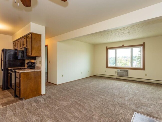 Sala de estar alfombrada con cocina conectada - Tourville Apartments