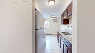 Located at 3530 18th Ave S in Minneapolis, MN, this one-bedroom, one-bathroom unit offers a thoughtfully laid-out single-floor living space. The galley-style kitchen is a standout feature, showcasing rich dark wood cabinetry with brushed nickel hardware, light granite countertops, a stainless steel sink, and white appliances including an electric range and refrigerator. Light-toned ceramic tile flooring runs throughout the kitchen, which also benefits from a window that brings in natural light and is equipped with a wall-mounted AC unit and ceiling fan for year-round comfort. A textured ceiling adds a classic touch overhead. The bedroom offers a cozy, carpet-floored retreat with neutral walls and a full-width sliding door closet, providing ample storage space. The bathroom features a timeless design with a mosaic tile floor, a vanity with wood cabinetry, a full tub-shower combination with white subway tile surround, and clean white fixtures throughout. The overall layout is efficient and functional, making excellent use of the available space to create a comfortable, livable home in a residential Minneapolis neighborhood.