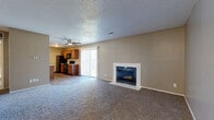 Located at 3221 SW Twilight Ct in Topeka, Kansas, this single-story unit offers a practical and comfortable layout designed for everyday living. The living room serves as the heart of the space, featuring plush carpeting, a white-surround fireplace as a focal point, and a sliding glass door fitted with vertical blinds that provides direct access to an outdoor patio and allows natural light to filter into the room. A ceiling fan overhead aids in air circulation throughout the open area.

Adjacent to the living room, the galley-style kitchen is well-appointed with warm medium-toned wood cabinetry lining both sides, light stone-finish countertops, a double-basin sink, and wood-look flooring. Black appliances, including a refrigerator, range, microwave, and dishwasher, are integrated throughout.

The bedrooms are carpeted and neutral in tone, each offering closet storage and windows that bring in outside light. One bedroom features a standard reach-in closet, while another includes a built-in shelving closet system.

The bathroom includes a white vanity with a speckled countertop, an inset sink with brushed nickel hardware, and a well-lit mirror above. Textured ceilings are consistent throughout the unit, contributing to a cohesive interior aesthetic.