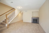 This two-floor home is thoughtfully laid out across its levels, offering a functional and comfortable living environment. The main floor opens to a spacious living room anchored by a tile-surround fireplace with a built-in niche above, providing a natural focal point in the room. Plush neutral carpeting flows throughout the living areas, complementing the warm beige wall tones found consistently across the home. Adjacent to the living room, the kitchen features honey-toned wood cabinetry, a stainless steel dishwasher, and tile flooring, with a window allowing natural light to fill the space. A carpeted staircase with a classic wood banister and white balusters connects the main floor to the upper level. Also on the lower level is a hallway area with access to additional rooms and exterior doors. Upstairs, the primary bedroom stands out with vaulted ceilings, a ceiling fan, a mirrored closet, a walk-in closet, and an en-suite bathroom. Additional bedrooms are carpeted and include ceiling fans and windows with blinds. The bathrooms feature tile flooring, warm wood vanity cabinetry, white countertops, and tub-shower combinations with built-in shelving.
