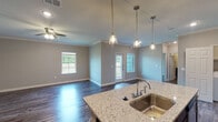 This single-story, 1-bedroom, 1-bathroom residence in Beaumont, Texas offers a thoughtfully designed open-concept layout that maximizes both functionality and visual appeal. Rich, wood-look flooring flows continuously throughout the home, complemented by crown molding and neutral-toned walls that create a clean, cohesive aesthetic.

The kitchen serves as a central focal point, featuring dark espresso cabinetry, granite countertops, a subway tile backsplash, and stainless steel appliances including a side-by-side refrigerator, range, and microwave. A kitchen island with a granite surface and undermount sink provides additional workspace, while pendant lighting overhead adds a stylish touch. A built-in pantry with open shelving and additional cabinetry offers ample storage.

The open living area is generously proportioned, featuring a ceiling fan, recessed lighting, and access to an outdoor balcony through a glass-panel door flanked by windows that invite natural light. The bedroom is a comfortable retreat with its own ceiling fan and continued wood-look flooring.

The bathroom includes a subway-tiled soaking tub and shower combination, dark vanity cabinetry with granite countertops, and direct access to a walk-in closet with built-in shelving. An in-unit laundry area rounds out this well-equipped home.