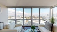 Located at 1 Harbor Point Road in Stamford, Connecticut, this two-bedroom, two-bathroom residence offers a refined urban living experience defined by contemporary design and expansive natural light. Floor-to-ceiling windows span the living areas, framing sweeping panoramic views of the Stamford skyline and waterfront that serve as a constant backdrop throughout the home.

The open living room is anchored by rich hardwood flooring and large corner windows that flood the space with daylight, creating a bright and airy atmosphere. Adjacent, the dining area features access to a private balcony, further enhancing the connection to the city views. The kitchen is outfitted with stainless steel appliances, a gas range, and sleek wood cabinetry, combining functionality with modern style.

Both bedrooms are generously proportioned, each with plush carpeting and oversized windows that offer stunning elevated views. The primary bedroom enjoys a waterfront-facing outlook, adding a serene quality to the private retreat.

The two bathrooms are tastefully appointed, featuring dark wood vanities with undermount sinks, decorative tile flooring, and clean, contemporary fixtures. One bathroom includes a soaking tub, while both maintain a polished and cohesive aesthetic throughout this well-designed urban residence.