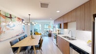Located at 645 E Ocean Blvd in Long Beach, California, this well-designed two-bedroom, two-bathroom unit offers a thoughtfully arranged single-level floor plan that maximizes its compact footprint. The open-concept main living area seamlessly integrates the kitchen, dining, and living spaces, creating an efficient and inviting layout. The kitchen features warm wood cabinetry, stainless steel appliances including a built-in microwave and oven, a white quartz countertop, subway tile backsplash, and a stainless steel sink. A modern multi-bulb pendant light anchors the dining area, which comfortably accommodates a full-sized table and chairs. The living room receives natural light through multiple windows and offers a relaxed, open atmosphere. Light wood-tone flooring flows consistently throughout the main areas, complementing the neutral palette. The primary bedroom includes dual sliding-door closets and direct access to a private en-suite bathroom finished with white tile flooring and wood-toned vanity cabinetry. A second bathroom mirrors the clean, modern aesthetic. The entry hallway provides practical access to all rooms, completing this streamlined, contemporary layout.