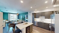 Located at 132 Unity St in Irvine, CA, this single-floor residence offers a well-appointed open-concept design that seamlessly connects the kitchen, dining, and living areas. The kitchen is a standout feature, equipped with stainless steel appliances including a gas range, built-in microwave, and French door refrigerator. Flat-panel gray cabinetry pairs with white quartz countertops and a marble-style backsplash, while a center island with a built-in wine cooler provides additional prep space and seating. Light wood-style flooring flows throughout the main living areas, enhancing the bright, airy atmosphere.

The living room is distinguished by a bold teal accent wall, large windows that draw in natural light, and views of the surrounding community. Bedrooms feature wood-style flooring, generous windows, and statement lighting fixtures with a modern brass finish.

The bathrooms are finished with notable detail: the primary bath includes a dual-sink vanity with illuminated LED mirrors and gray herringbone tile flooring, while a secondary bath features deep-toned herringbone wall tile surrounding a soaking tub. Recessed lighting throughout the home contributes to a clean, contemporary ambiance.