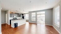 Located in the heart of downtown Indianapolis on E Market Street, this 1-bedroom, 1-bathroom residence offers a thoughtfully designed open-concept layout. The combined kitchen and living area serves as the centerpiece of the home, where warm hardwood-style flooring flows throughout and large windows flood the space with natural light while framing views of the surrounding cityscape. A sliding door provides access to a balcony, further enhancing the connection to the outdoors.

The kitchen is outfitted with dark cabinetry, granite countertops, a large center island with seating potential, pendant lighting, stainless steel appliances, and a tile backsplash — offering both functionality and style. Track lighting adds additional illumination to the cooking and prep areas.

The bedroom is a comfortable, carpeted retreat featuring multiple windows that continue the theme of natural light and city views. It is supported by ample closet space, with four closets distributed throughout the unit.

The bathroom includes a full tub-shower combination with white subway tile surround, hardwood-style flooring, and granite vanity countertops consistent with the home's overall finishes. An in-unit laundry area adds everyday convenience. Neutral gray walls and clean white trim complete the modern, cohesive aesthetic throughout.