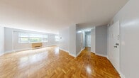 Located at 700 John F. Kennedy Boulevard in Weehawken, NJ, this well-appointed two-bedroom, one-bathroom residence offers a thoughtfully designed layout across a generous single floor. Light-toned hardwood flooring runs throughout, lending a clean, cohesive feel to the entire space.

The expansive living area is a standout feature, showcasing large sliding windows that invite abundant natural light and offer views of the surrounding greenery and city skyline. Built-in glass shelving adds a functional architectural detail to one wall, complemented by a built-in radiator unit. The open flow connects seamlessly to a dedicated dining area, highlighted by a pendant light fixture, which sits adjacent to the kitchen. The kitchen features white cabinetry with ample counter space and a classic tile floor.

The primary bedroom is notably spacious, finished in soft blue-gray tones with large windows framing outdoor views and a generous walk-in closet. The second bedroom also benefits from natural light through its own window. The full bathroom is finished in crisp white tile, featuring a tub/shower combination, vanity with storage, and a mirrored medicine cabinet. Three closets and an in-unit laundry area round out this well-equipped residence.