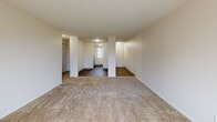 This two-bedroom, one-bathroom residence in Portland, Oregon offers a practical and well-organized single-level layout. The combined living and dining area is a welcoming, open space finished with plush carpeting and a textured ceiling, with a sliding glass door that leads to a private balcony overlooking a green outdoor area, filling the room with natural light. Structural columns define the transition between the living space and the kitchen, which features wood-look hardwood-style flooring, gray shaker-style cabinetry, light quartz countertops, a stainless steel sink, and a window that brightens the workspace. A hallway connects the living areas to the two carpeted bedrooms, each offering a quiet retreat with windows providing natural light and baseboard heating. Both bedrooms include closets with shelving, and the primary bedroom features a spacious walk-in style closet. The full bathroom is finished with wood-look tile flooring, a gray vanity, and a tub-shower combination. Three closets throughout the unit provide ample storage. The neutral color palette and clean finishes throughout create a move-in ready environment well-suited for comfortable everyday living in North Portland.