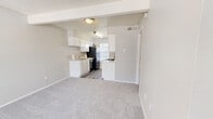 Located at 400 SW Gordon St in Burleson, TX, this one-bedroom, one-bathroom unit offers a thoughtfully organized single-floor layout designed to maximize every square foot. The galley-style kitchen is a functional highlight, featuring white cabinetry with granite-style countertops, black appliances including a refrigerator, electric range, and dishwasher, and wood-look vinyl flooring that adds a clean, modern touch. Natural light filters in through a window at the end of the kitchen, brightening the space. The living area flows naturally from the kitchen and is finished with neutral carpet, providing a comfortable and versatile space. The bedroom is a well-proportioned retreat with soft carpeting, a ceiling fan with light fixture, a window with blinds allowing natural light, and direct access to a dedicated closet with hanging space. The bathroom is neatly finished with a white vanity cabinet, granite-style countertop, a framed mirror, and textured walls that complement the overall neutral palette. Throughout the unit, textured ceilings, neutral gray tones, and consistent finishes create a cohesive and understated aesthetic well-suited for comfortable everyday living.