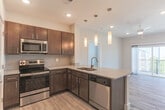 Located along Shore Drive in Norfolk, Virginia, this single-floor unit offers a thoughtfully designed layout with modern finishes throughout. The open-concept living area features light wood-style flooring and a ceiling fan, flowing seamlessly into the kitchen, which is appointed with rich dark cabinetry, granite-look countertops, stainless steel appliances including a range and microwave, and a stylish tile backsplash. A breakfast bar with pendant lighting adds both function and visual interest to the space. Sliding glass doors lead from the main living area to a private balcony, offering elevated views of the surrounding waterfront and marina — a standout feature of this property. The bedrooms are generously sized, finished with plush carpeting and large windows that bring in natural light and frame views of the marina and neighboring buildings. Each bedroom provides direct access to a bathroom, with the bathrooms featuring wood-look tile flooring and clean white tub-shower combinations with brushed metal fixtures. The neutral color palette of soft gray and warm white tones throughout creates a calm, cohesive ambiance, while the overall layout ensures a practical and comfortable living environment with easy connectivity between all rooms.