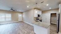 Located at 4763 Mac Rd in Valdosta, Georgia, this single-story home presents a clean, contemporary design with a cohesive neutral color palette carried throughout. The open-concept living and dining area is bright and welcoming, with recessed lighting, a ceiling fan, and multiple windows that invite natural light across the wood-look laminate flooring. A elegant chandelier adds a refined touch to the dining space.

The kitchen is well-appointed with white shaker-style cabinetry, granite countertops, and stainless steel appliances including an electric range, over-the-range microwave, and refrigerator. A peninsula with a built-in sink provides additional prep space and casual seating, while pendant lighting enhances the area's functionality and style. Adjacent to the kitchen is a dedicated laundry closet with utility connections.

The bathrooms continue the home's consistent design language, featuring granite-topped white vanities, wood-look flooring, and tub/shower combinations. One bathroom also includes a separate walk-in shower alongside the soaking tub.

An attached garage offers ample storage and parking, accessed via an automatic opener, with a utility panel conveniently located nearby. The overall ambiance is fresh, neutral, and move-in ready.