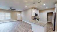 Located at 4763 Mac Rd in Valdosta, Georgia, this single-story home presents a clean, contemporary design with a cohesive neutral color palette carried throughout. The open-concept living and dining area is bright and welcoming, with recessed lighting, a ceiling fan, and multiple windows that invite natural light across the wood-look laminate flooring. A elegant chandelier adds a refined touch to the dining space.

The kitchen is well-appointed with white shaker-style cabinetry, granite countertops, and stainless steel appliances including an electric range, over-the-range microwave, and refrigerator. A peninsula with a built-in sink provides additional prep space and casual seating, while pendant lighting enhances the area's functionality and style. Adjacent to the kitchen is a dedicated laundry closet with utility connections.

The bathrooms continue the home's consistent design language, featuring granite-topped white vanities, wood-look flooring, and tub/shower combinations. One bathroom also includes a separate walk-in shower alongside the soaking tub.

An attached garage offers ample storage and parking, accessed via an automatic opener, with a utility panel conveniently located nearby. The overall ambiance is fresh, neutral, and move-in ready.